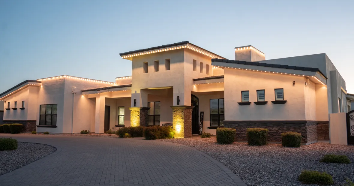 A permanent-lighting install lit warm at dusk on a desert home